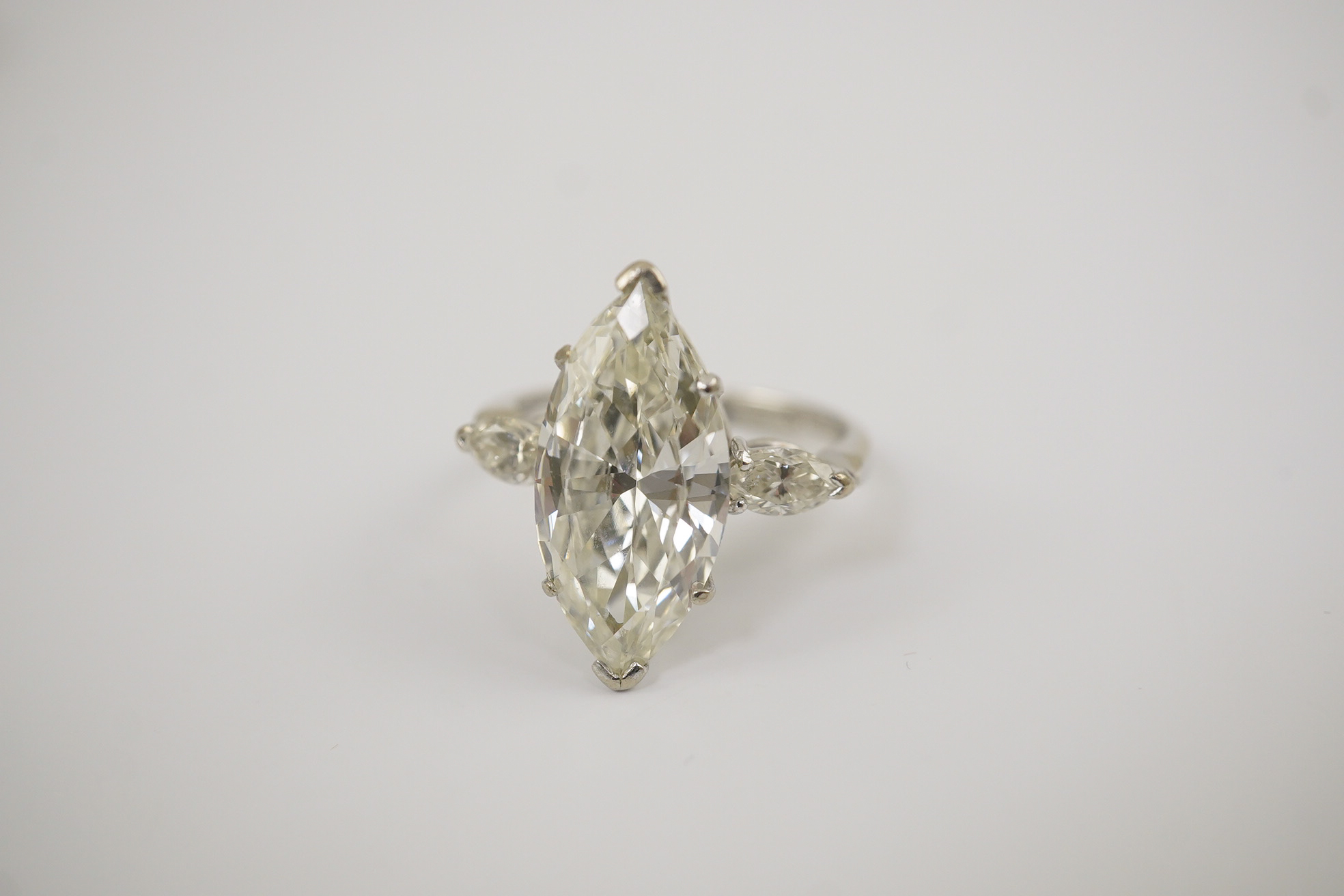 A modern 18ct white gold and single stone marquise cut diamond set ring, with two stone marquise cut diamond set shoulders